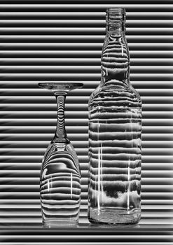 Empty bottle and turned glass with bands of reflection blinds