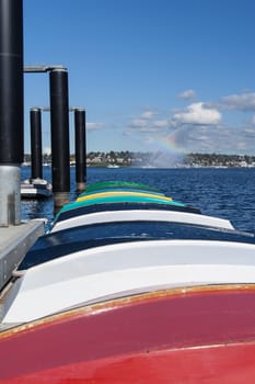 Colorful rowboats on a dock with a fireboat in the background