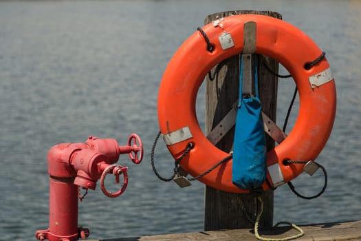 Life ring hanging on a pier with a red valve next to it