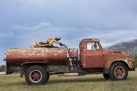 A blonde model posing with an old truck in an outdoor environment