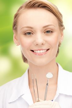 people, medicine, stomatology and healthcare concept - happy young female dentist with tools over green background