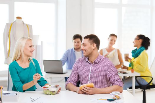 startup, education, fashion, food and office concept - smiling fashion designers having lunch at office