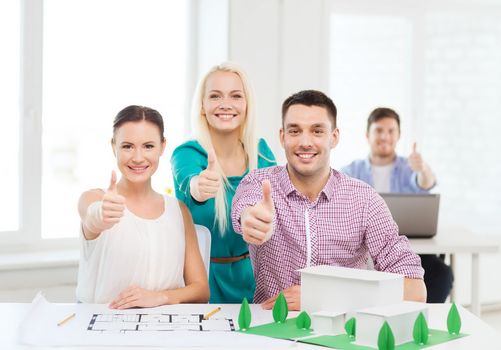 startup, education, architecture and office concept - smiling architects with house model and blueprint in office showing thumbs up