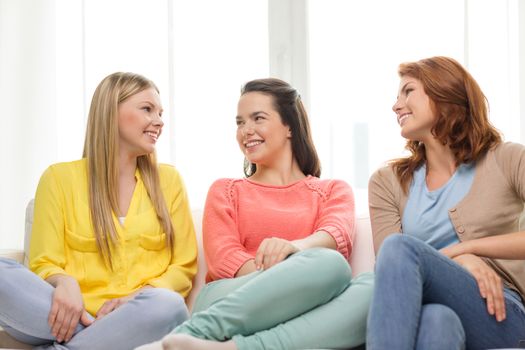 friendship and happiness concept - three girlfriends having a talk at home