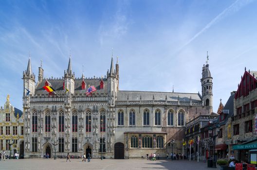 Bruges, Belgium - May 11, 2015: Tourist on Burg square with City Hall and Basilica of the Holy Blood in Bruges, Belgium on May 11, 2015. The historic city centre is a prominent World Heritage Site of UNESCO.