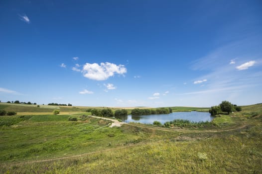 Blue lake on a green meadow in the summer