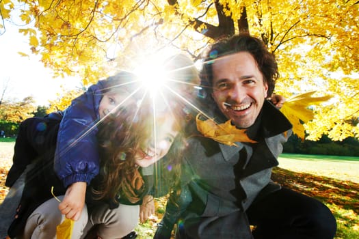 Portrait of a happy family in autumn park with maple leaves