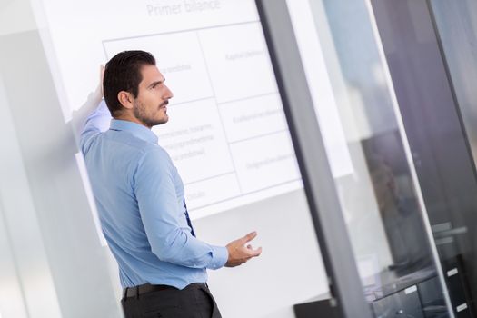 Business man making a presentation in front of whiteboard. Business executive delivering a presentation to his colleagues during meeting or in-house business training. 