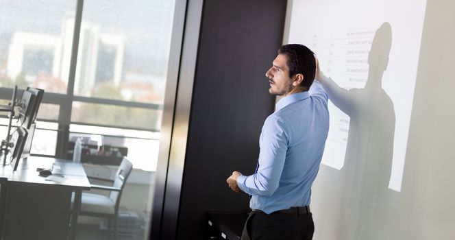 Business man making a presentation in front of whiteboard. Business executive delivering a presentation to his colleagues during meeting or in-house business training. 