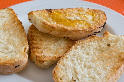 in the picture slice bread toasted with honey on white dish at restaurant.