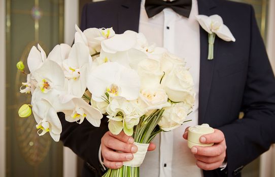 The groom with wedding rings and bouquet