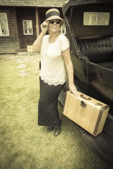 Happy 1920s Dressed Girl Holding Suitcase Next to Vintage Car and Cabin.