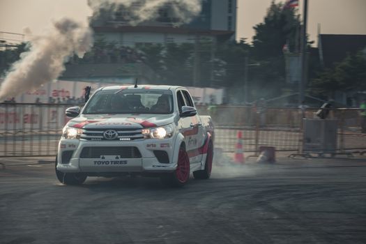 Udon Thani, Thailand - October 18, 2015: Toyota Hilux Revo perform drifting contest on the track between driver from Thailand and Japan at the event Toyota Motor Sport show at Udon Thani, Thailand with motion blur of the background and smoke of the burning tires