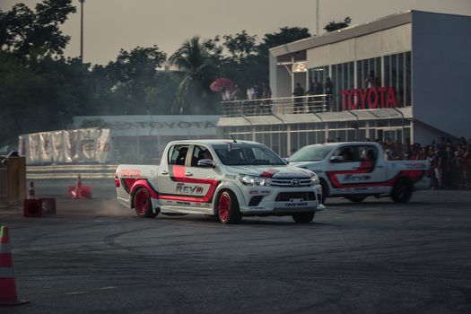 Udon Thani, Thailand - October 18, 2015: Toyota Hilux Revo perform drifting contest on the track between driver from Thailand and Japan at the event Toyota Motor Sport show at Udon Thani, Thailand with motion blur of the background and smoke of the burning tires