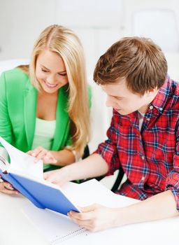 education concept - smiling students reading book at school