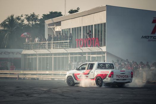 Udon Thani, Thailand - October 18, 2015: Toyota Hilux Revo perform drifting contest on the track between driver from Thailand and Japan at the event Toyota Motor Sport show at Udon Thani, Thailand with  smoke of the burnout tires