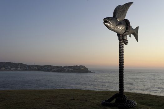 AUSTRALIA, Sydney: The Sculpture by the Sea exhibition in Sydney is photographed here on October 26, 2015 as the sun rises. The sculptures can be seen between Bondi and Tamarama and runs from October 22 to November 8, 2015. Artist: Gillie & Marc Schattner - Flying Fish