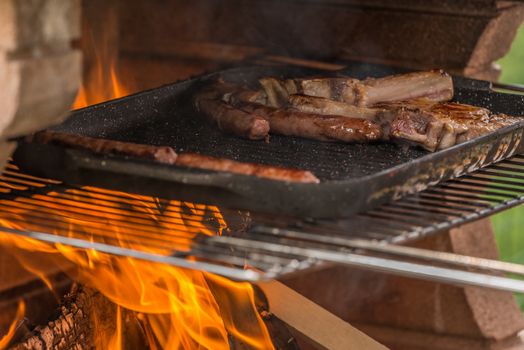 In the picture of sausages and veal chop while being cooked on the fireplace (Barbecue).