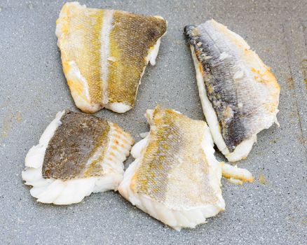 Pictured three fillets of sea bream and codfish cooked on the grill outdoor.