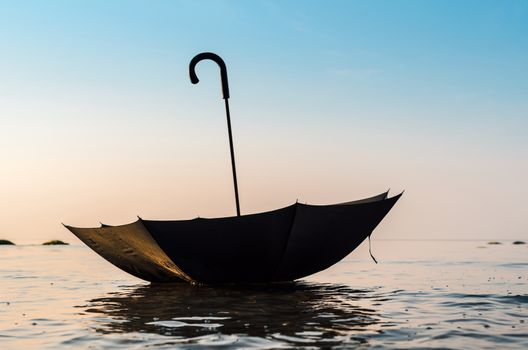 Open black umbrella on the sea surface