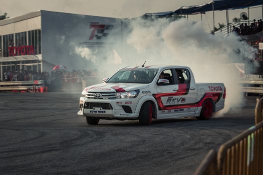 Udon Thani, Thailand - October 18, 2015: Toyota Hilux Revo perform drifting contest on the track between driver from Thailand and Japan at the event Toyota Motor Sport show at Udon Thani, Thailand with motion blur of the background and smoke of the burning tires