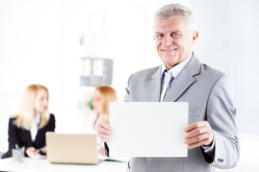 Happy senior businessman holding Blank business card in the office. Looking at camera. Selective Focus.