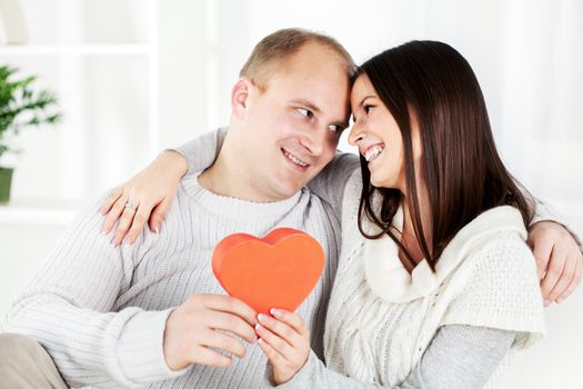 Happy beautiful Young couple in home interior with heart shaped box. The valentine's day.