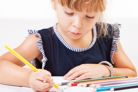 Cute little girl drawing with colored pencils at home.