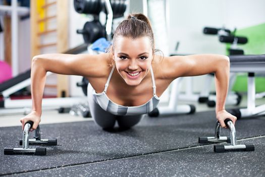 Cute Young girl doing push-ups in gym. Front View.