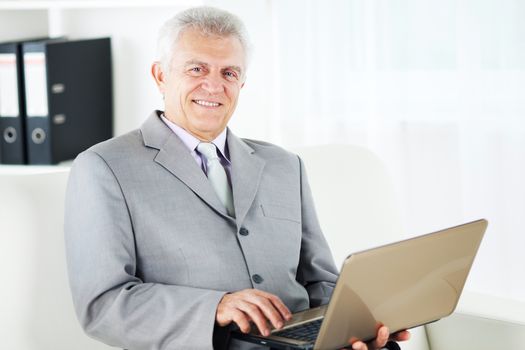 Happy Senior businessman working at home on laptop.