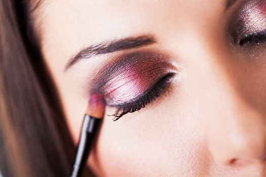 Attractive young woman applying eyeshadow. Close-up.