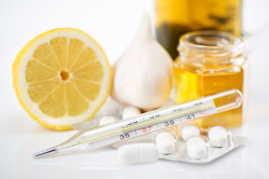 Vitamins and pills for treatment Cold And Flu. Lemon, tea, honey, garlic and Thermometer on white background.