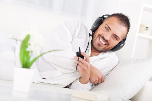 Beautiful young man resting and listening music at home.