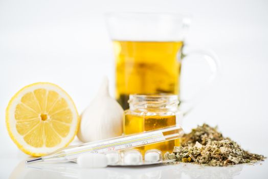 Vitamins and pills for treatment Cold And Flu. Lemon, tea, honey, garlic and Thermometer on white background.