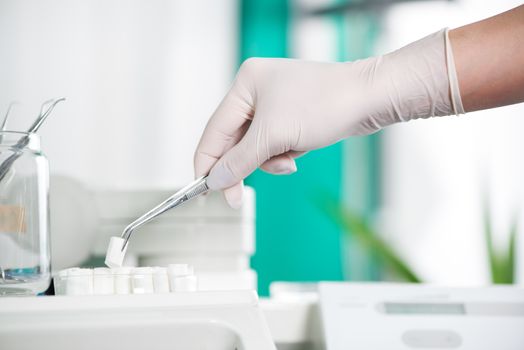 Dentist holding Dental Tweezers with coton pad. Selective Focus.