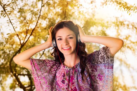 Happy Young Woman standing in the Beautiful Nature, enjoy in sunny day and Listening Music.