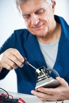 Senior adult Electrician checking and repairing old iron.