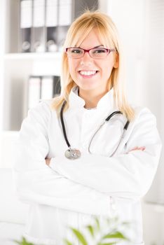 Portrait of a young woman doctor with stethoscope standing in her office.