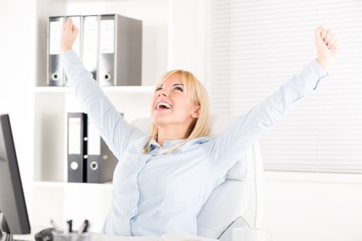 Happy Businesswoman in the office with raised arms.