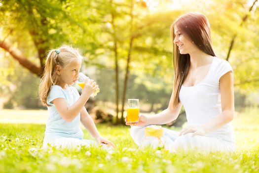 Beautiful Mother and daughter in the nature having little picnic.