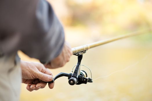 Fisherman holding Fishing Rod with Reel. Selective focus. Focus on Reel.