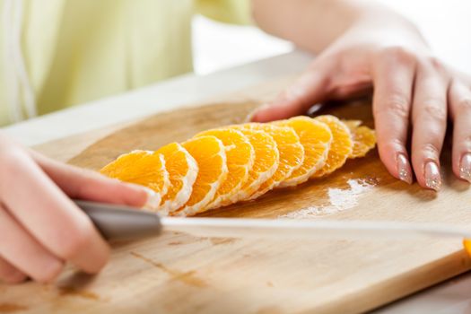 Female hands Cutting Orange in a kitchen. Close-up. Selective Focus.
