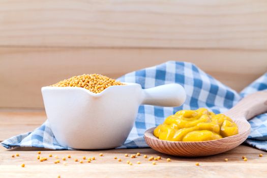 Composition of mustard and mustard seeds on wooden background.