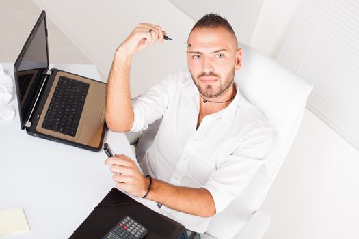 Attractive businessman sitting at the table and thinking about a business problem.