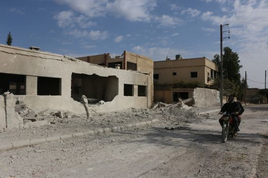 SYRIA, Damascus: A Syrian man drives a scooter amid damaged buildings in the Marj al-Sultan neighborhood in eastern Damascus on October 24, 2015.