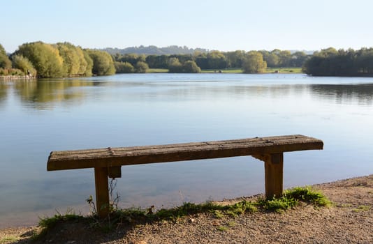 Empty rustic bench at the edge of a quiet lake