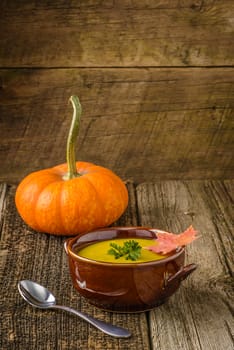 Bowl of creamy homemade pumpkin soup on a rustic wood background.
