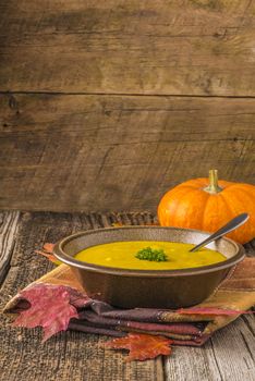 Bowl of homemade pumpkin soup photographed on a rustic wood background.
