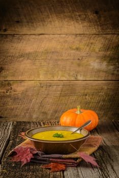 Creamy homemade pumpkin soup on a rustic wooden background.