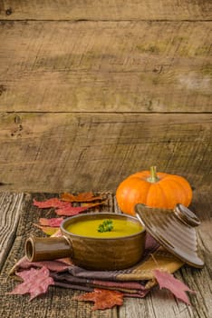 Bowl of hot creamy pumpkin soup photographed on an autumn themed background.